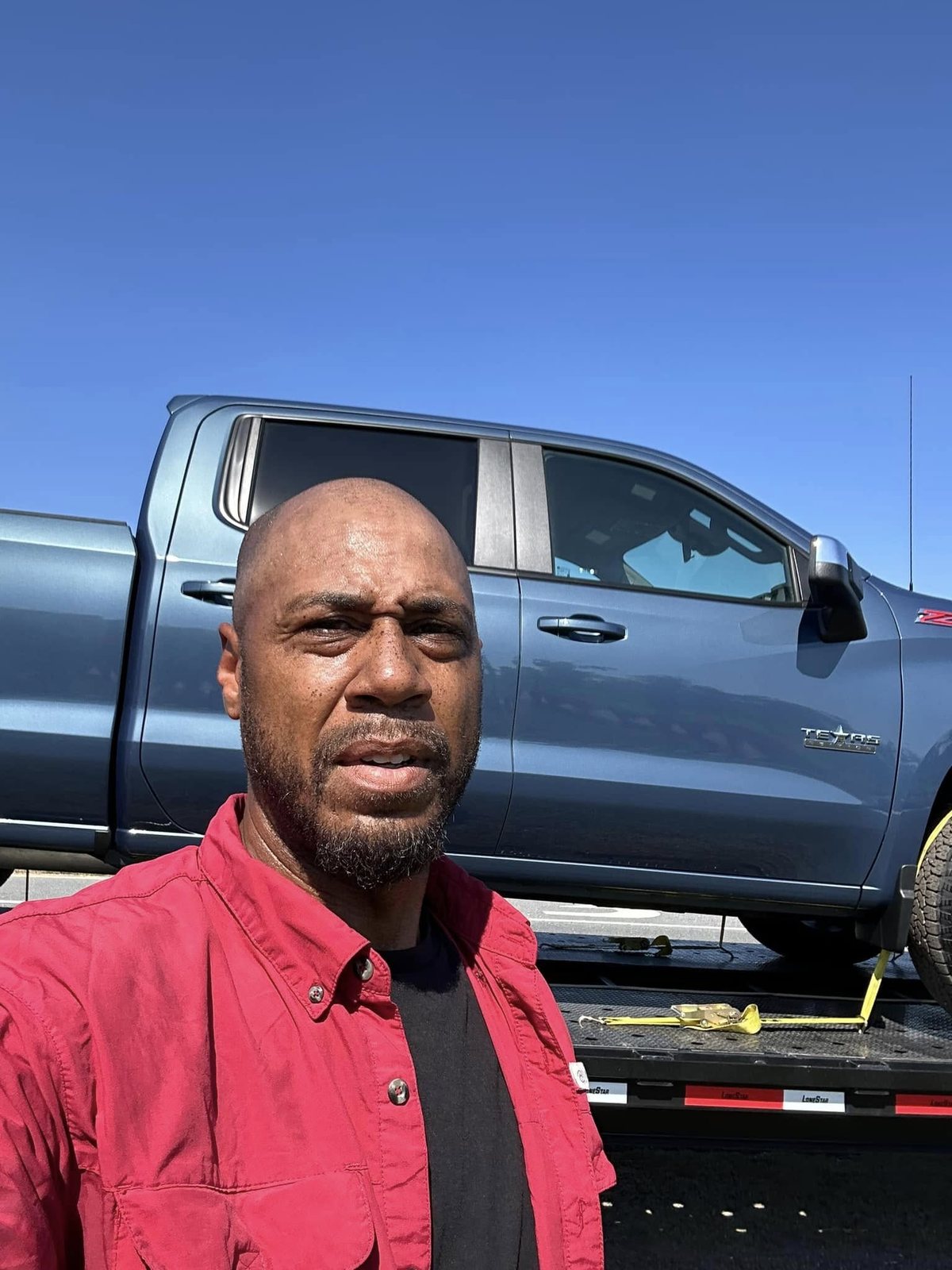 Donald Welburn standing with a vehicle loaded on his flatbed for transport