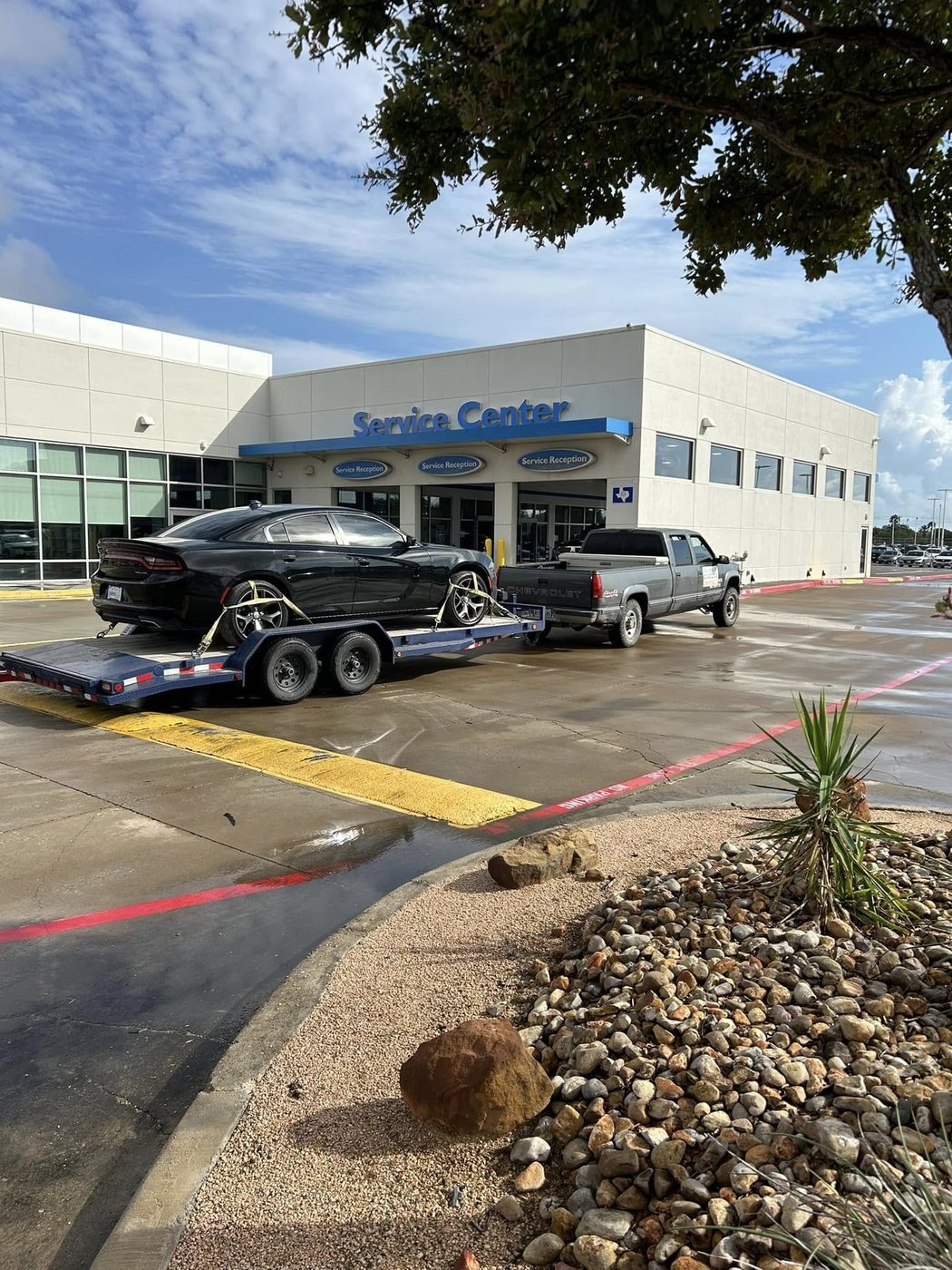 A black muscle car loaded on the flatbed at a dealership