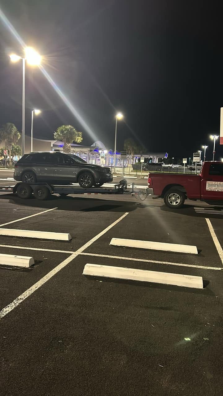 A vehicle being recovered on the flatbed in a lot at night