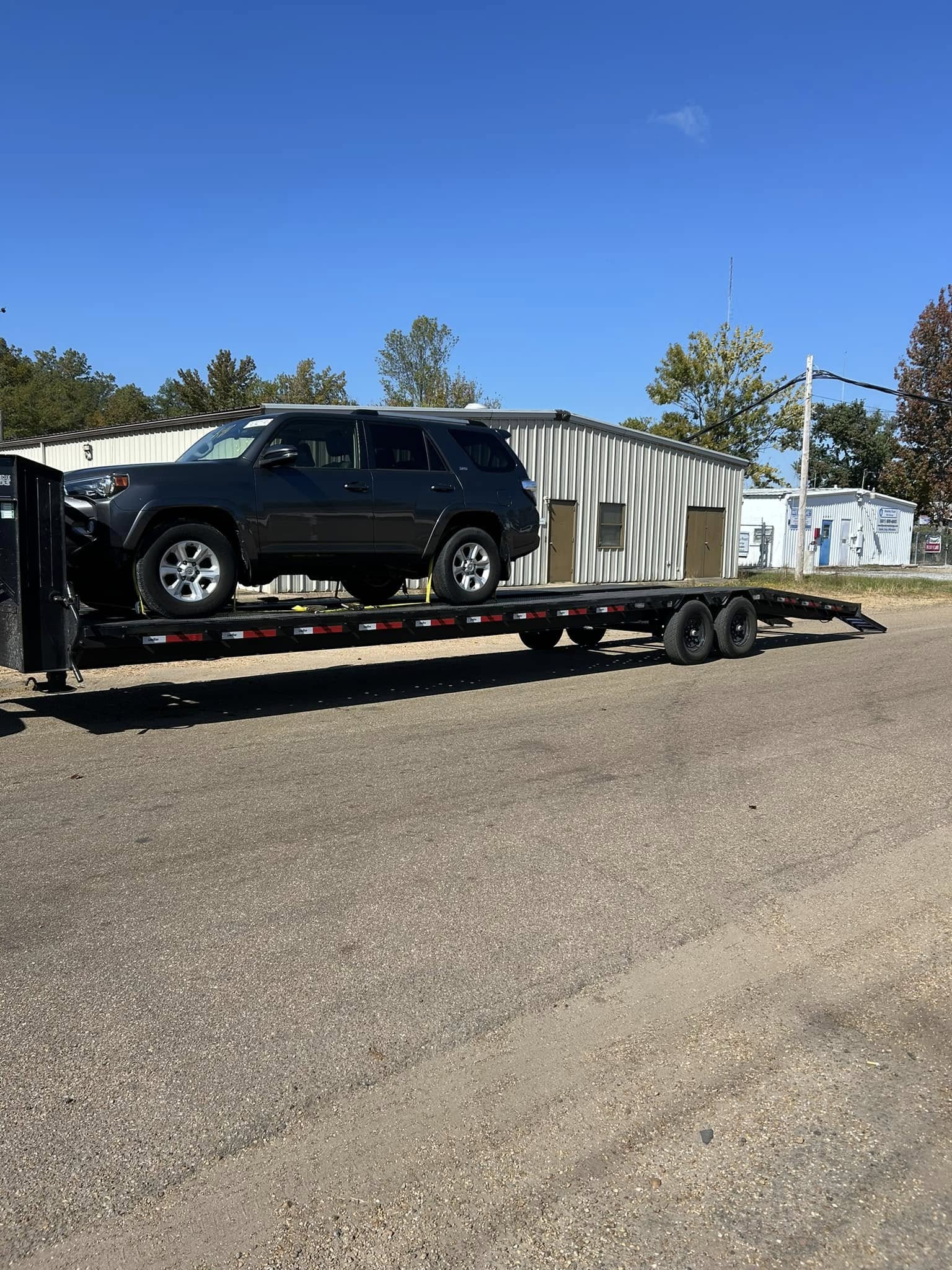 An SUV strapped down on the gooseneck flatbed, ready for transport