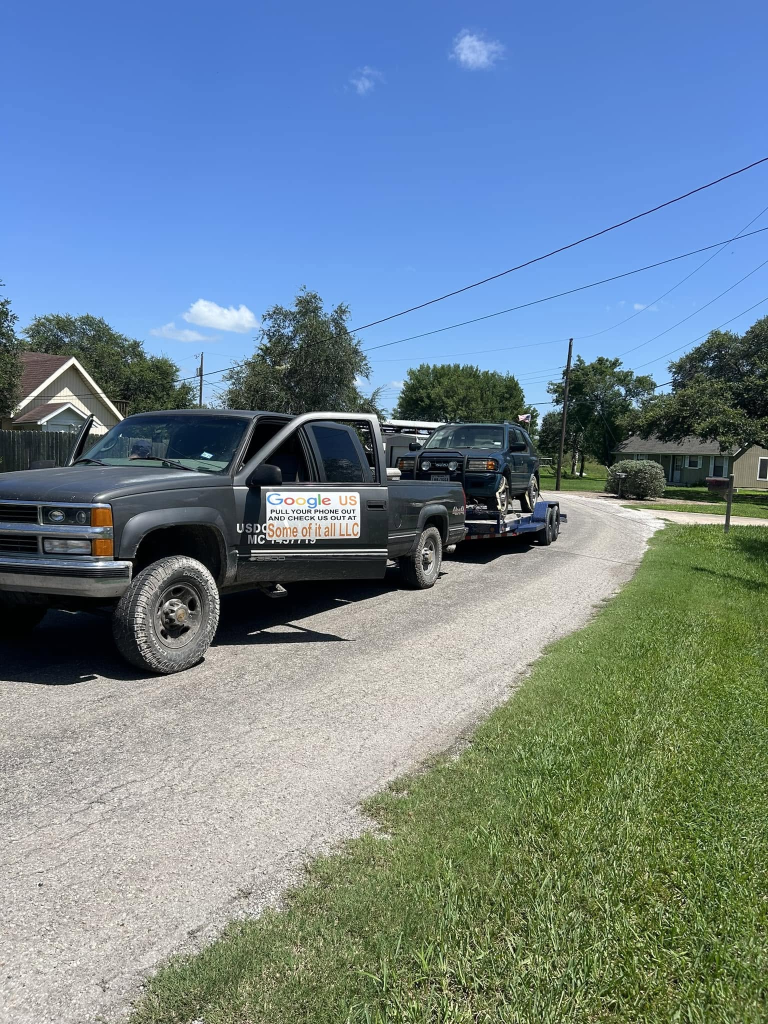 Some Of It All truck towing an SUV on a flatbed trailer